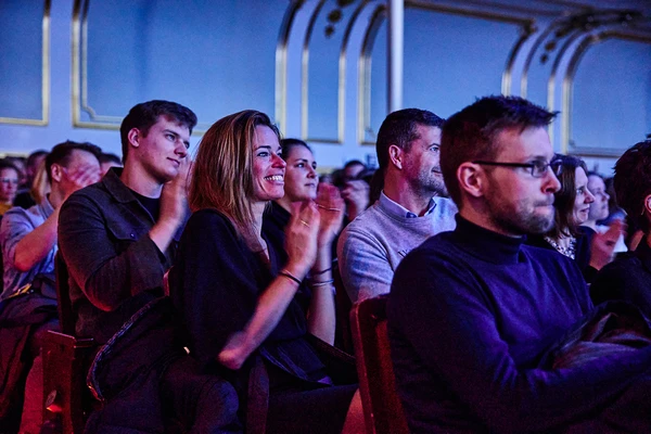 Zuschauer applaudieren während einer Veranstaltung in einem stilvollen Saal.